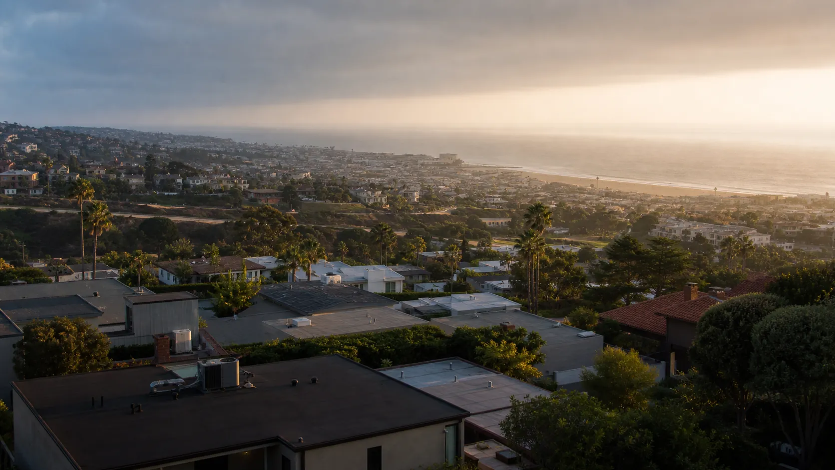 Elevated view over South Bay Los Angeles coastal neighborhoods descending toward Redondo and Torrance beaches, with the Pacific and marine-layer fog on the horizon
